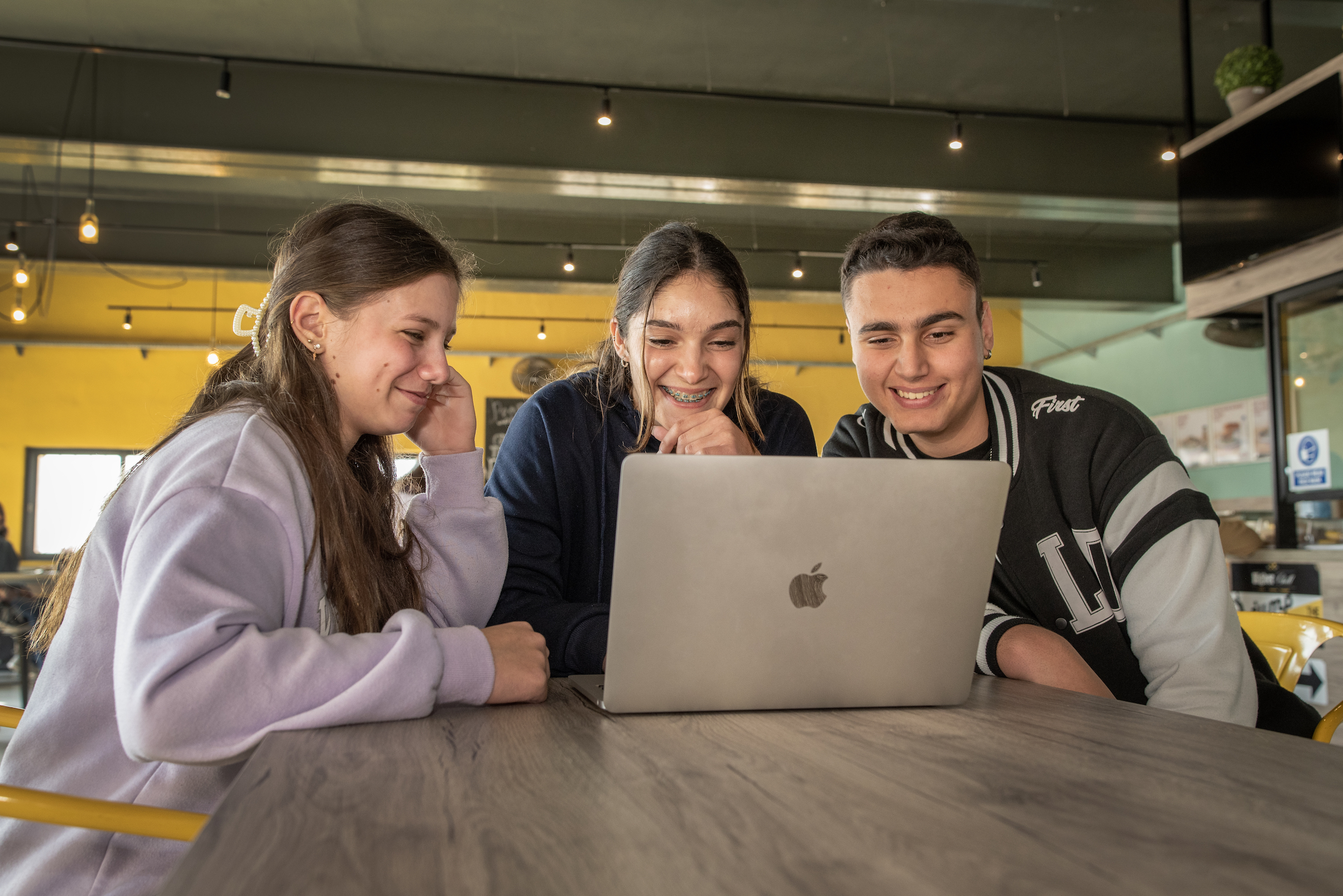 three students watching something on a laptop